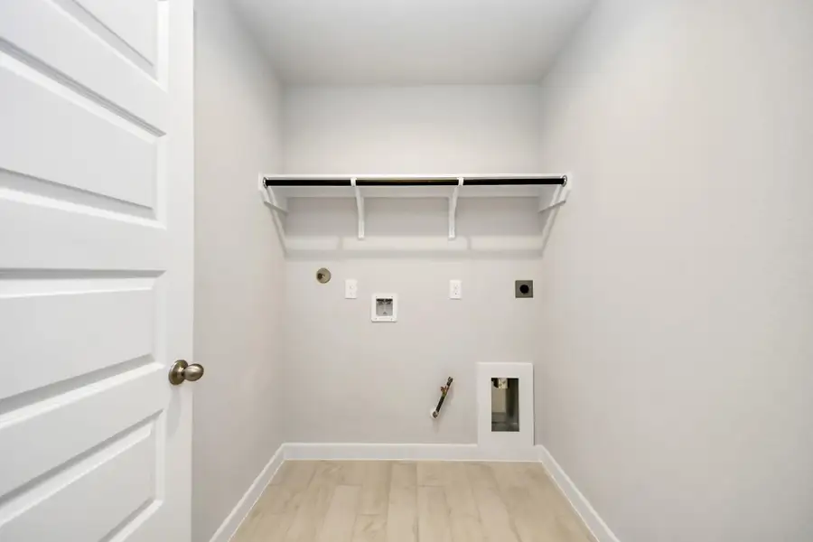 A perfect blend of functionality and comfort. Capture the essence of easy living with a first-floor laundry room, thoughtfully equipped with shelving for effortless organization. Both electric and gas connections available. Sample photo of completed home with similar floor plan. Actual colors and selections may vary.