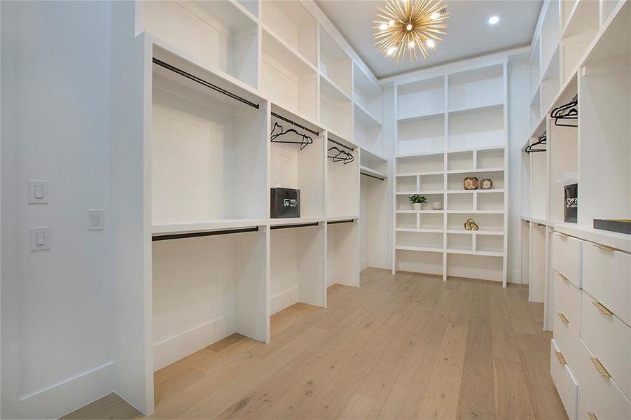 Walk in closet with light wood-type flooring and a chandelier