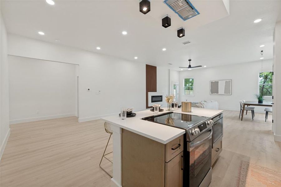 Modern kitchen island with integrated range and oven, complemented by white countertops and wood-finish cabinetry