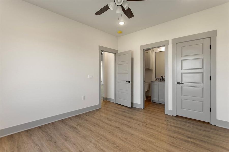 Unfurnished bedroom featuring connected bathroom, ceiling fan, light hardwood / wood-style flooring, and sink