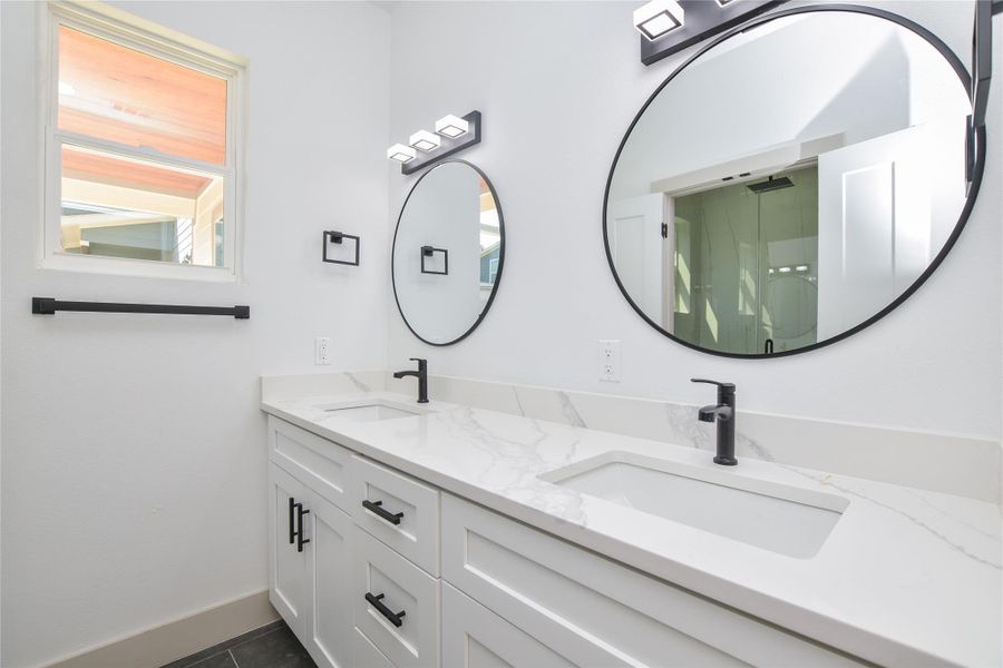 Primary bathroom on main level. Dual vanity with quartz countertops. Good storage and attractive mirrors.