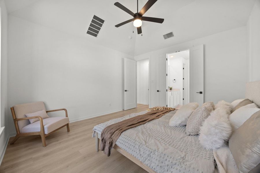 Bedroom featuring light wood-style flooring, vaulted ceiling, a ceiling fan, and ensuite bathroom
