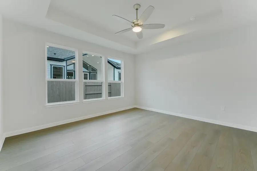 Empty room featuring a tray ceiling, wood finished floors, and a ceiling fan