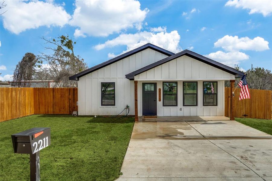 View of front of house featuring board and batten siding, a front yard, and fence