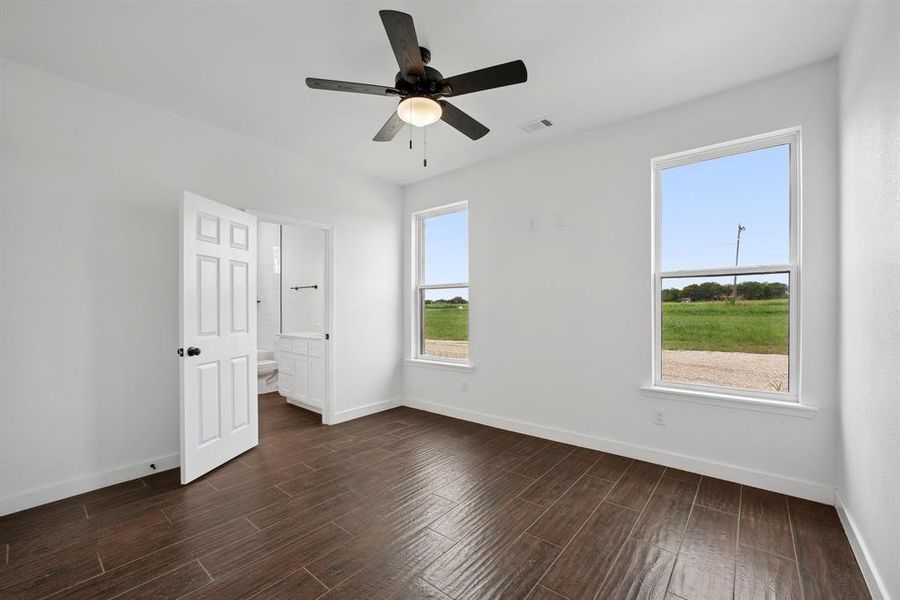 Unfurnished bedroom with wood tiled floors, connected bathroom, and ceiling fan