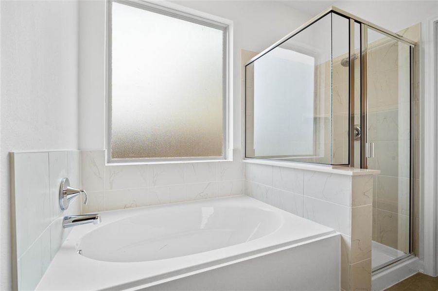 This primary bathroom is definitely move-in ready! Featuring a walk-in shower with tile surround, garden tub to soak after a long day, custom paint, tempered glass window for privacy and natural lighting, sleek and dark modern finishes.