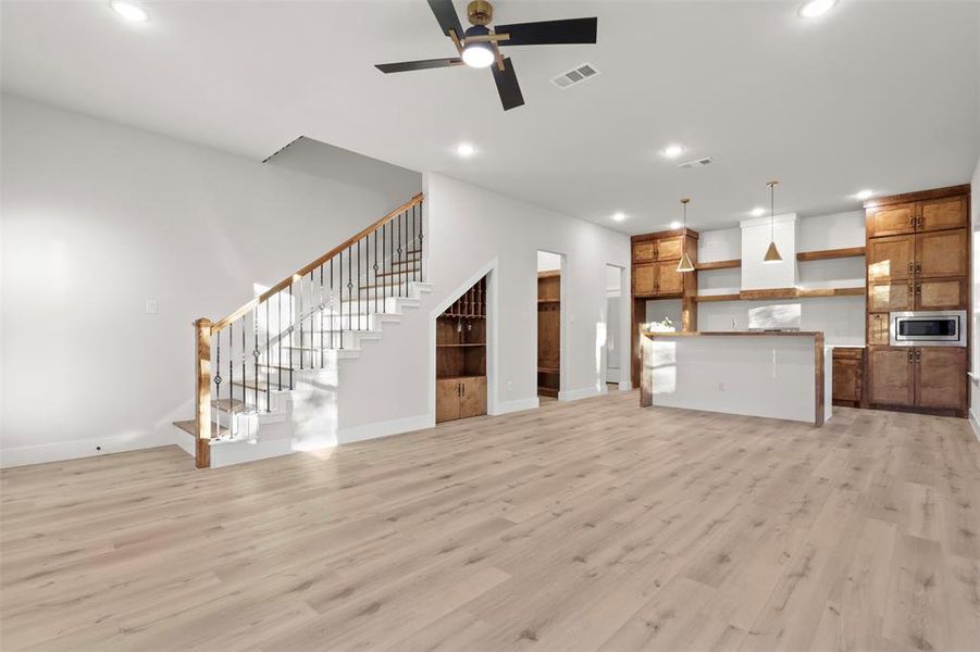 Unfurnished living room featuring ceiling fan and light hardwood / wood-style flooring