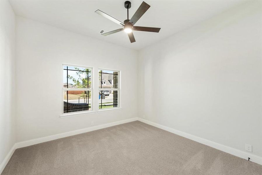 Room featuring two windows, neutral carpeting, white baseboards, and a modern ceiling fan with light fixture Room featuring two windows, neutral carpeting, white baseboards, and a modern ceiling fan with light fixture