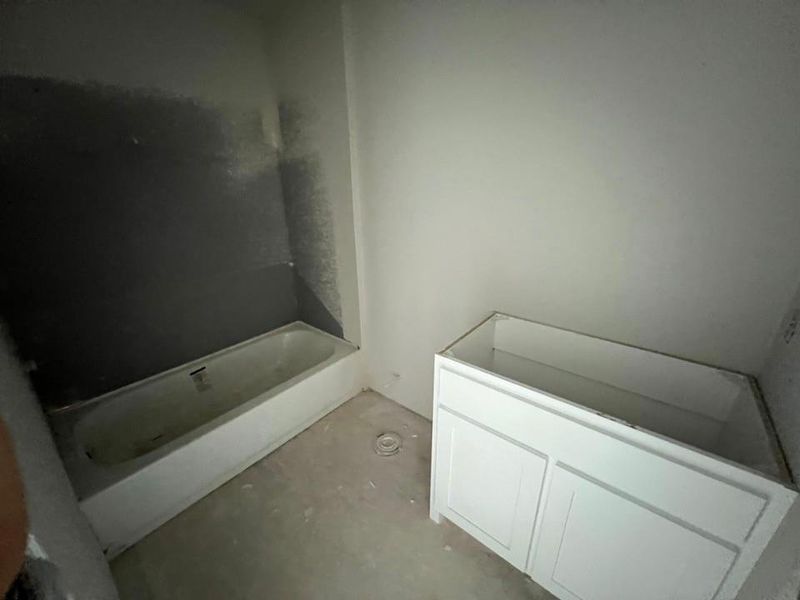Bathroom featuring a tub, vanity, and concrete flooring