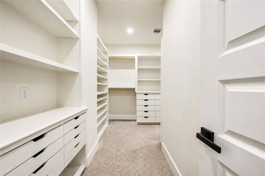 Spacious walk-in closet featuring ample shelving and custom built-in storage, perfect for organization.