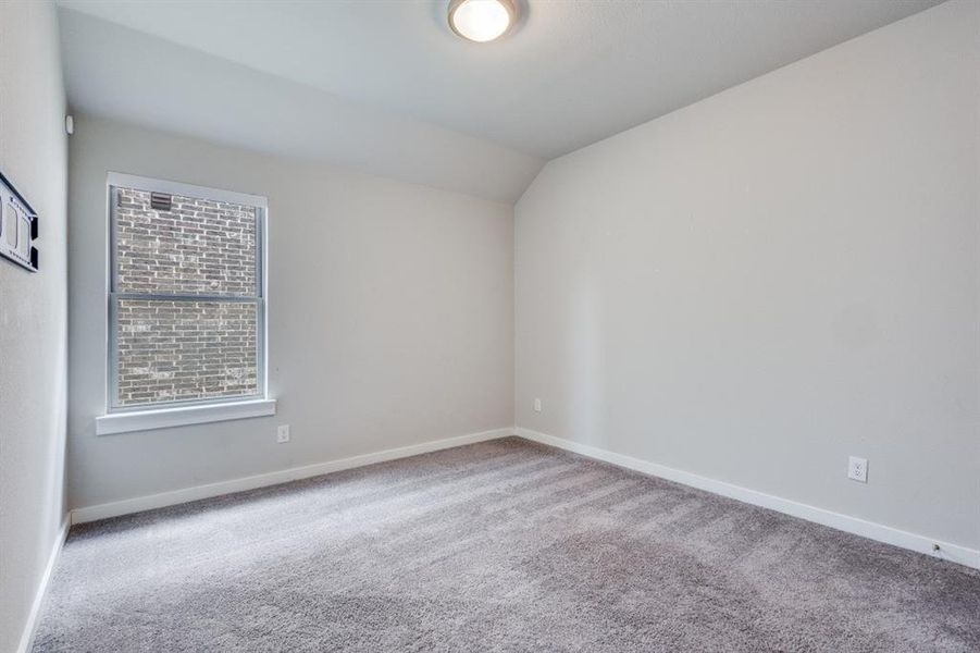 Carpeted spare room with lofted ceiling and baseboards Carpeted spare room with lofted ceiling and baseboards