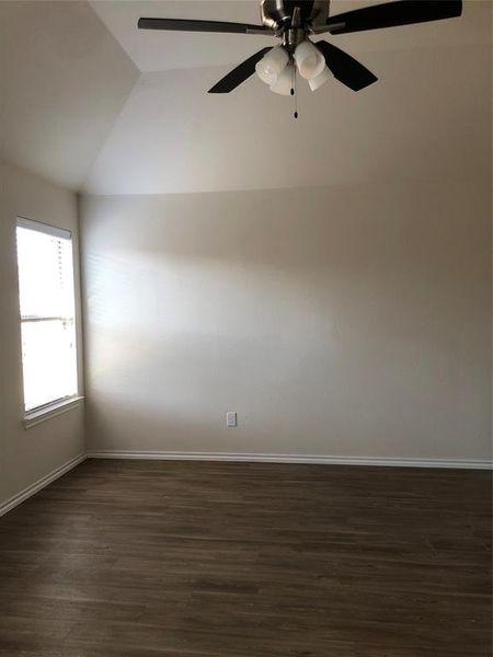 Unfurnished room featuring ceiling fan, dark wood-type flooring, and lofted ceiling