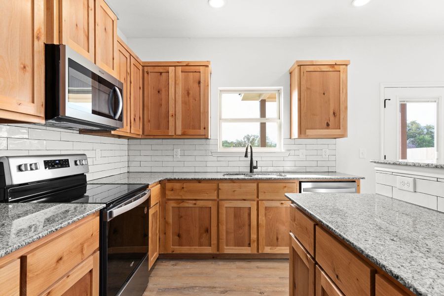 Kitchen featuring light wood-style floors, recessed lighting, a sink, stainless steel appliances, and decorative backsplash Kitchen featuring light wood-style floors, recessed lighting, a sink, stainless steel appliances, and decorative backsplash