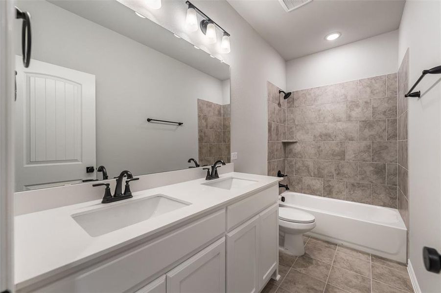Bathroom with double vanity, shower / bath combination, and light tile patterned floors Bathroom with double vanity, shower / bath combination, and light tile patterned floors