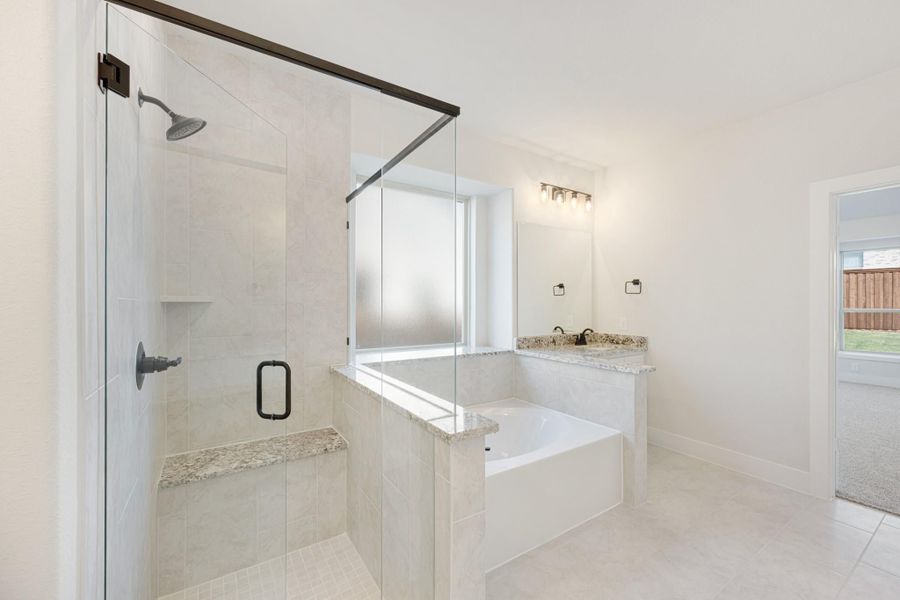 Master bathroom with glass walk-in shower, soaking tub, and granite countertop vanity with tile floors