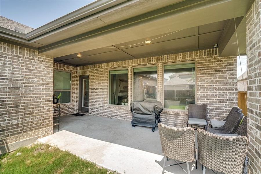 Covered patio featuring brick exterior walls, a concrete slab, and recessed lighting