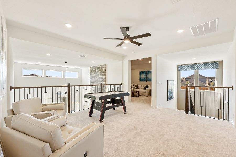 Upstairs game room with air hockey table, cream seating, carpet, and open railing overlooking lower level