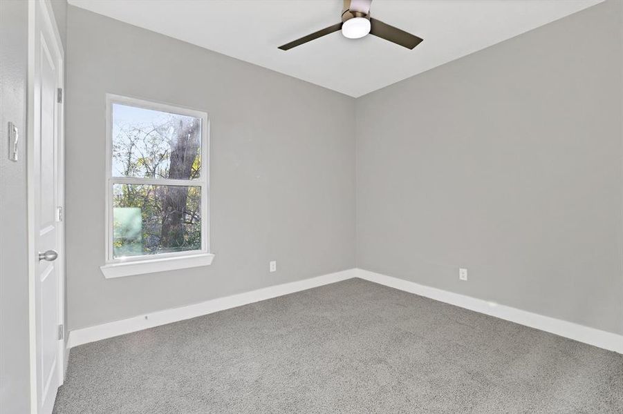 Carpeted empty room featuring ceiling fan