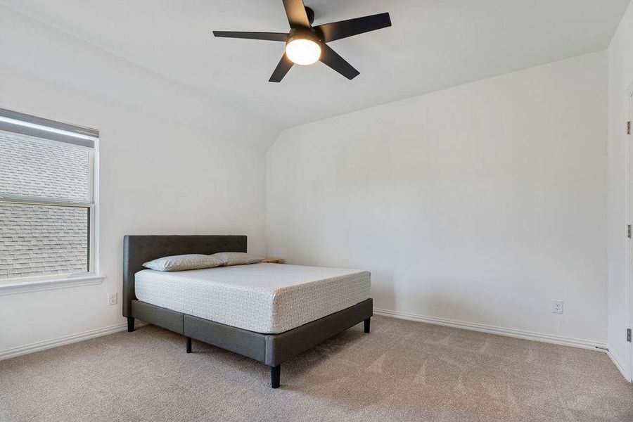 Bedroom featuring a ceiling fan, light colored carpet, and vaulted ceiling Bedroom featuring a ceiling fan, light colored carpet, and vaulted ceiling