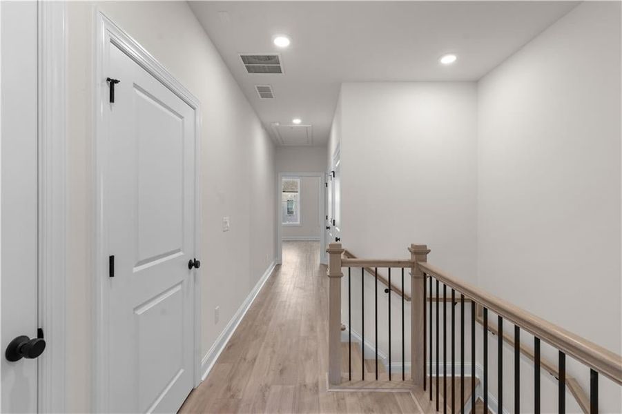 Corridor with attic access, light wood finished floors, recessed lighting, and an upstairs landing