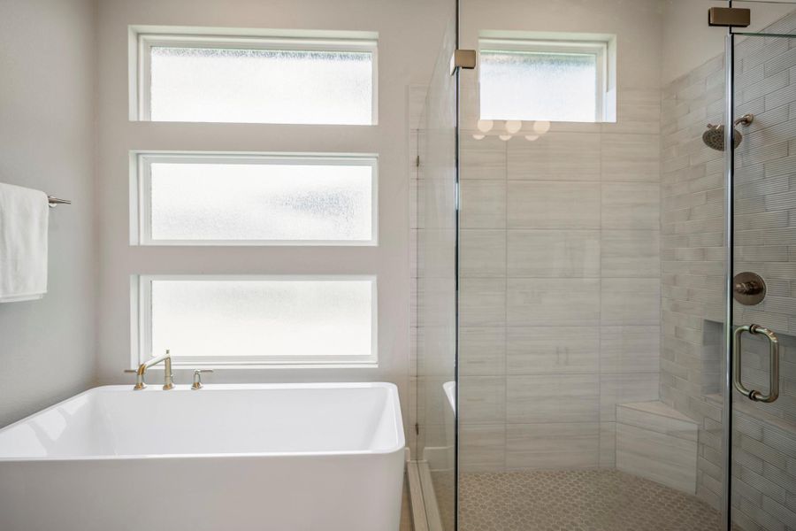 Designer details take center stage with a sleek freestanding tub, modern fixtures, frameless glass shower, beautiful tilework, updated hardware and privacy windows that fill the space with soft natural light.