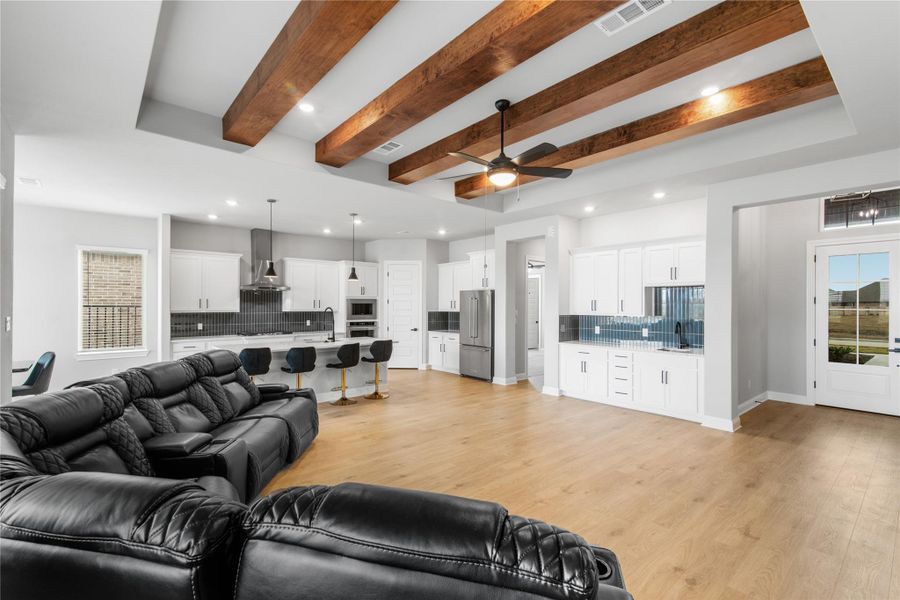 Spacious living area featuring elegant beams, stylish lighting, and a wet bar with ample storage.