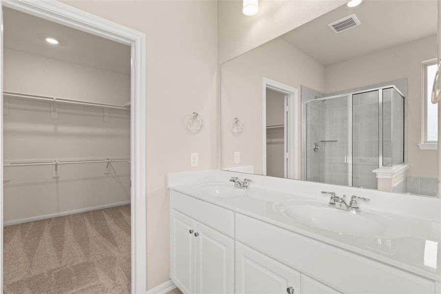 The en-suite primary bathroom offers a spa-like atmosphere with its elegant design, high end finishes, and tasteful lighting, creating a retreat within your own home.