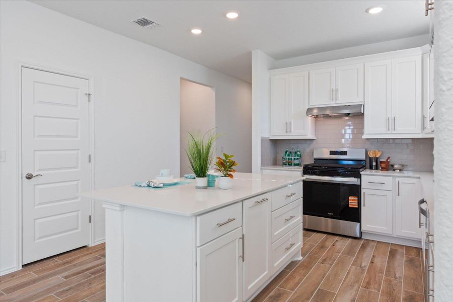 Kitchen featuring white cabinets, wood finish floors, appliances with stainless steel finishes, tasteful backsplash, and recessed lighting