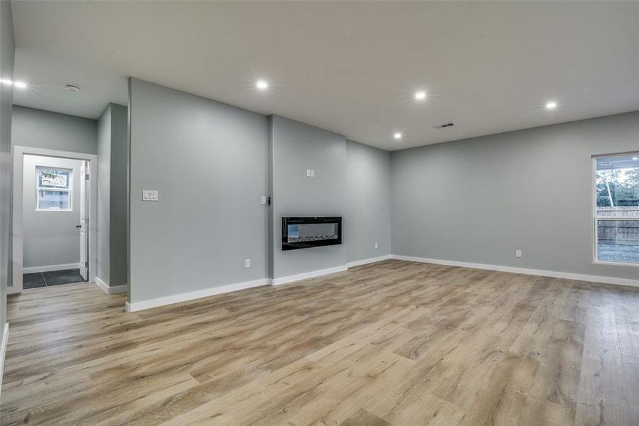 Unfurnished living room featuring light wood-type flooring and heating unit