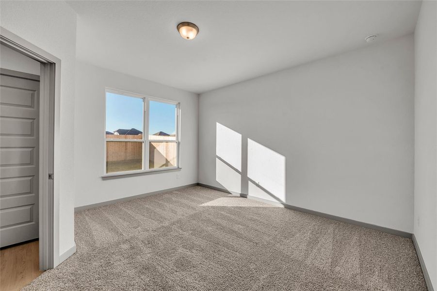 Unfurnished bedroom with light carpet and baseboards