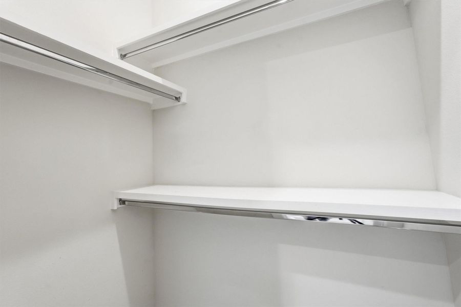 Spacious walk-in closet with built-in shelving and hanging space, offering ample storage and a clean, modern finish.
