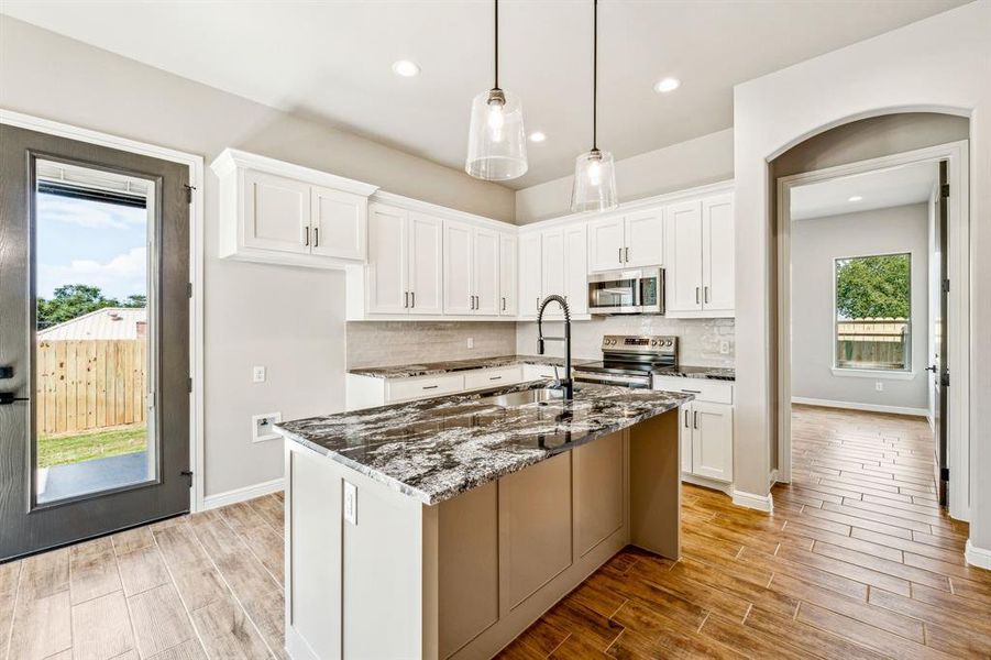 Kitchen featuring stainless steel appliances, backsplash, and white cabinets