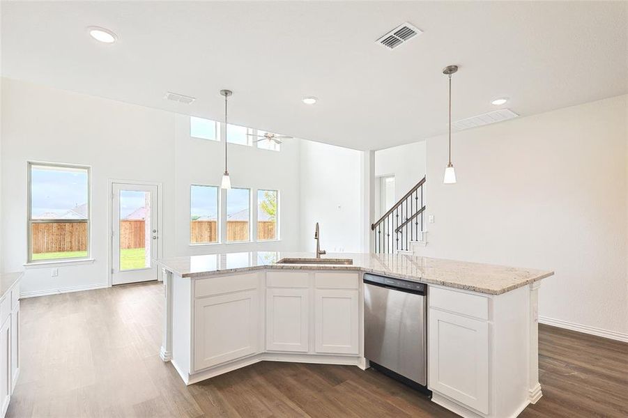 Kitchen featuring dishwasher, sink, decorative light fixtures, and white cabinetry