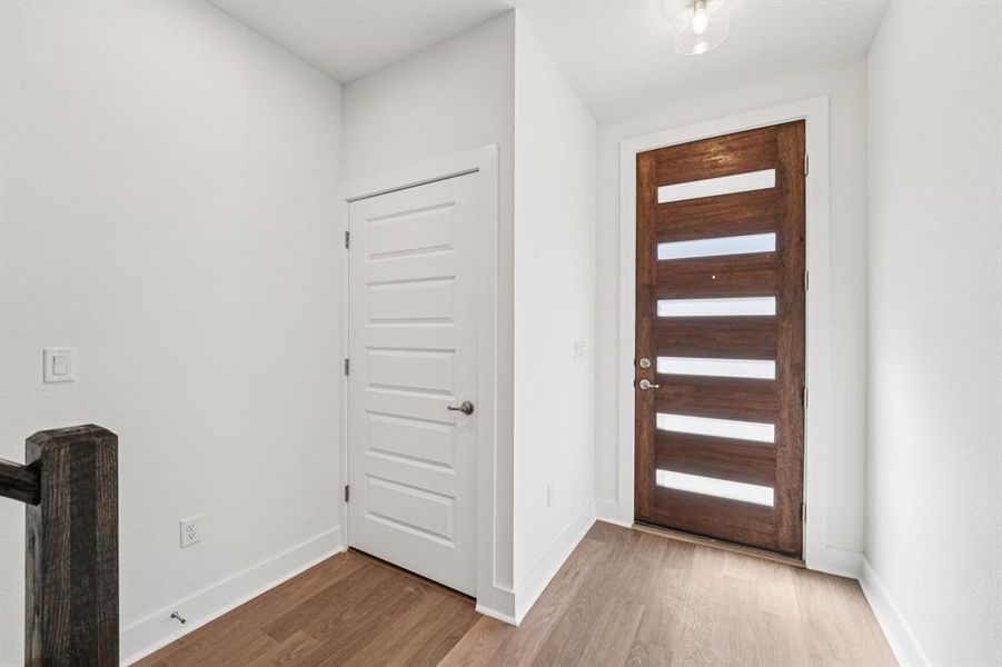 A modern front door, clean lines, and warm RevWood flooring give the lower level a simple, polished first impression  (Sample photo of finishes and layout)