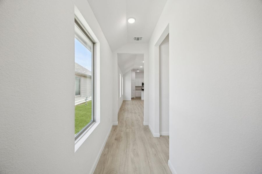 Hallway featuring light wood finished floors and vaulted ceiling