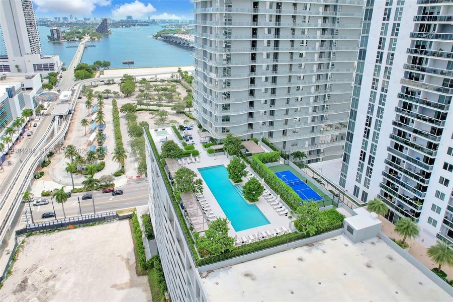 Rooftop amenities featuring a swimming pool, tennis court, and lush landscaping