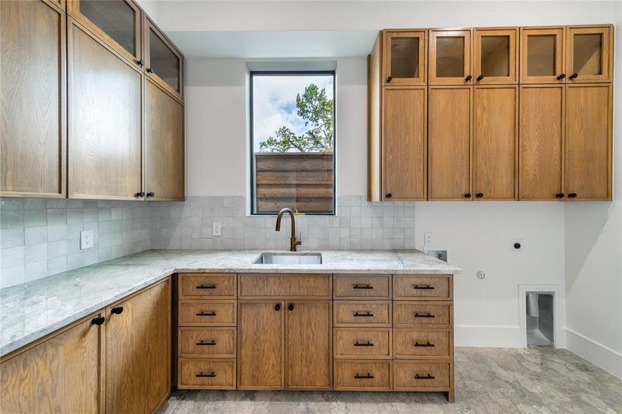 Kitchen with glass insert cabinets, light stone countertops, wood finish cabinets, and tasteful backsplash