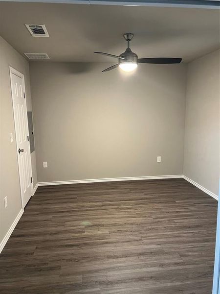 Spare room with ceiling fan, dark wood-style floors, and baseboards