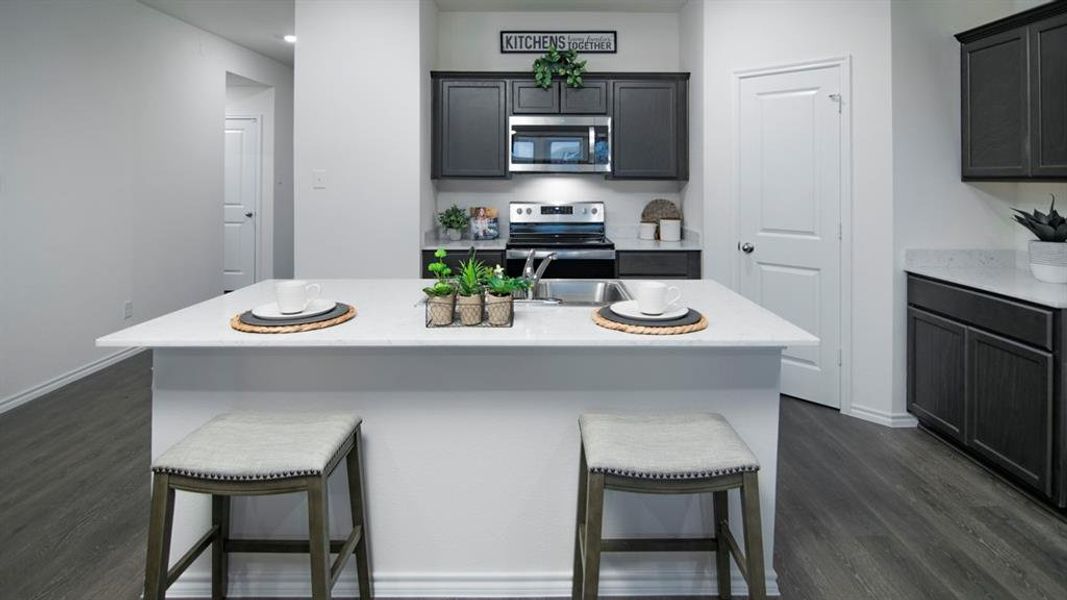 Kitchen with a kitchen bar, stainless steel appliances, dark wood-type flooring, and an island with sink