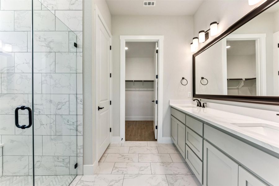 Bathroom with a spacious closet, a marble finish shower, light marble finish floors, and double vanity Bathroom with a spacious closet, a marble finish shower, light marble finish floors, and double vanity