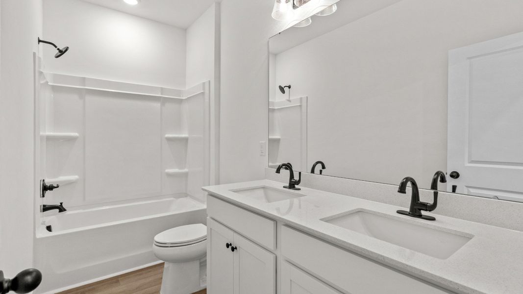 Secondary bath with dual vanity and tub, designed for both comfort and convenience.