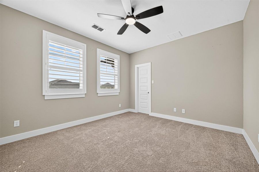 Secondary bedroom 3 upstairs with plantation shutters and ceiling fan.