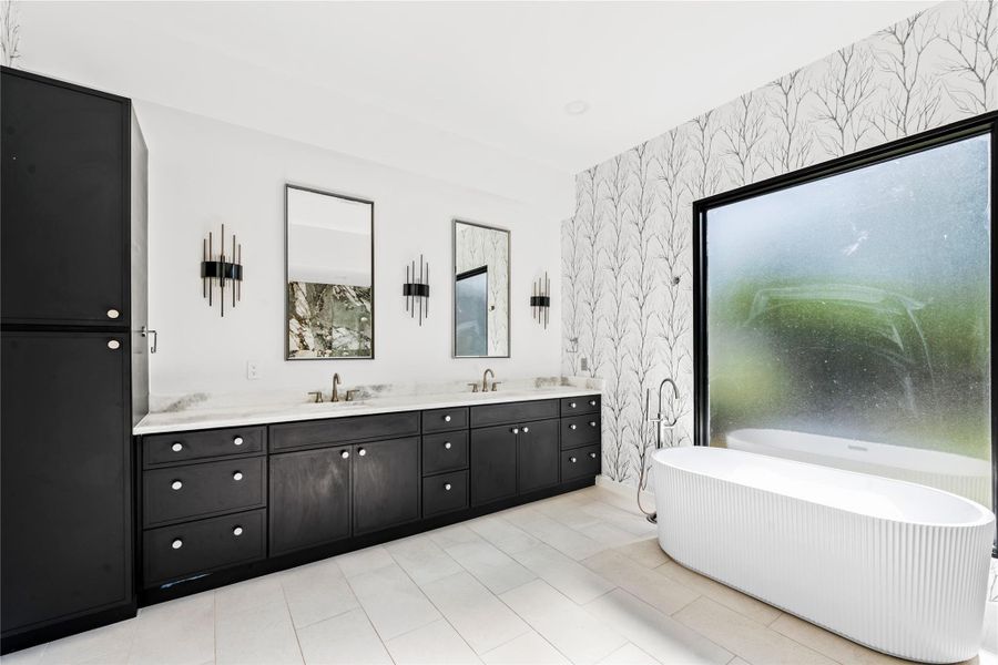 Full bath with double vanity, a freestanding tub, wallpapered walls, and light tile patterned floors