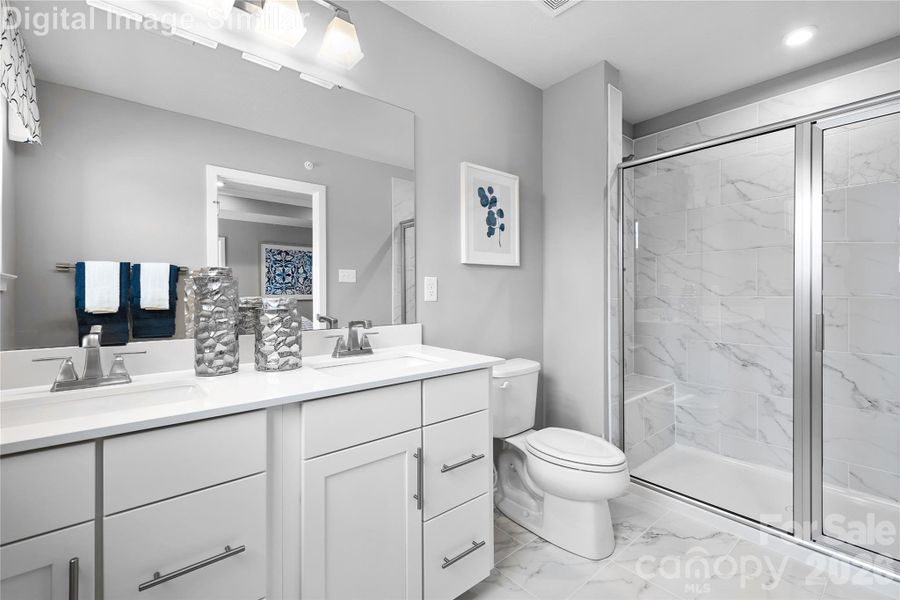 Private ensuite bath featuring optional sleek framed shower door, dual sinks with elegant fixtures, and built-in cabinetry for stylish, functional storage—your personal spa retreat. Private ensuite bath featuring optional sleek framed shower door, dual sinks with elegant fixtures, and built-in cabinetry for stylish, functional storage—your personal spa retreat.