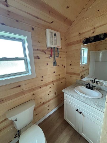 Bathroom featuring wooden walls, vanity, wood finished floors, and vaulted ceiling Bathroom featuring wooden walls, vanity, wood finished floors, and vaulted ceiling
