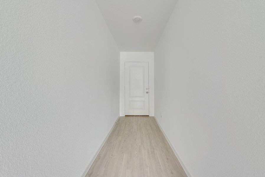 Corridor featuring light wood-style flooring and baseboards
