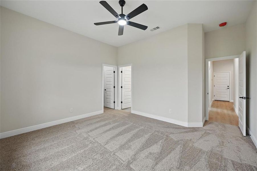 Unfurnished bedroom featuring light colored carpet and a ceiling fan Unfurnished bedroom featuring light colored carpet and a ceiling fan