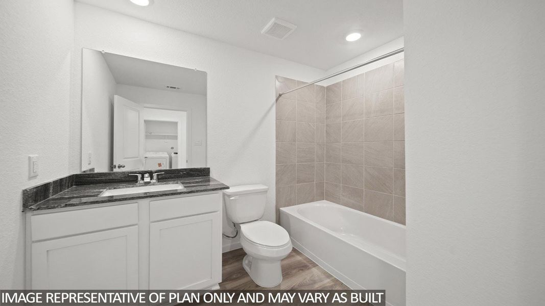 Bathroom featuring a white vanity with a dark speckled countertop, undermount sink, and a large wall-mounted mirror