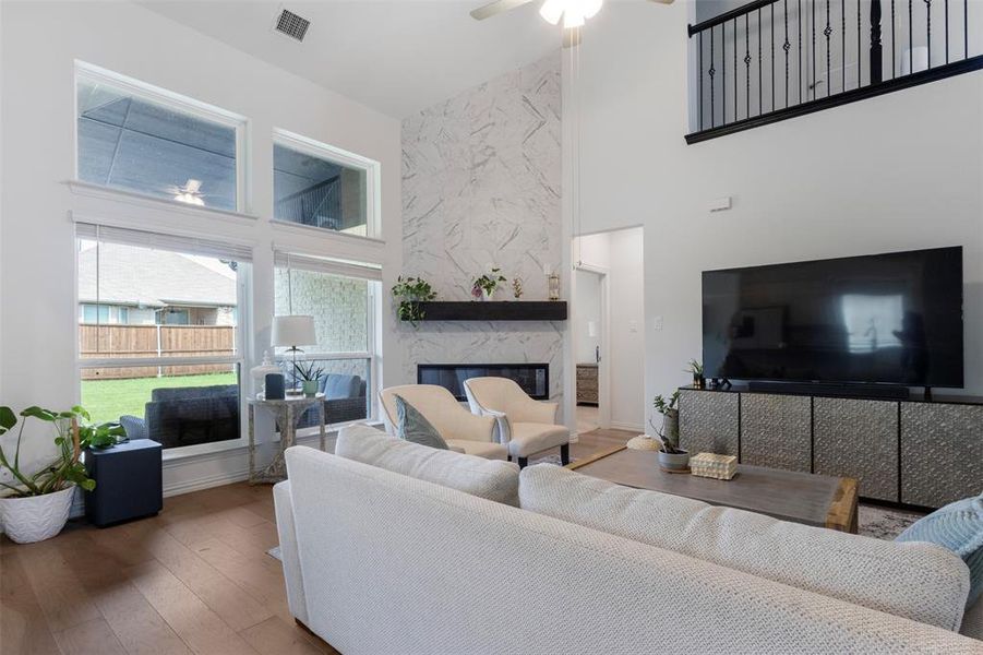Living room with a high ceiling, wood finished floors, a fireplace, and ceiling fan