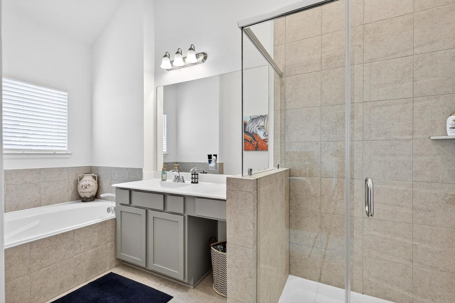 Private full bath with large vanity, framed mirror, and a combination of soaking tub and glass-enclosed shower. Private full bath with large vanity, framed mirror, and a combination of soaking tub and glass-enclosed shower.